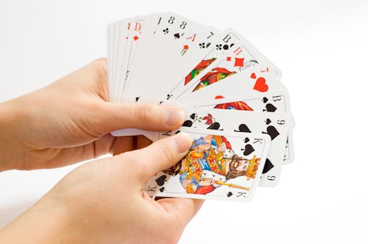 Colorful playing cards fanned out in hands against a white background.