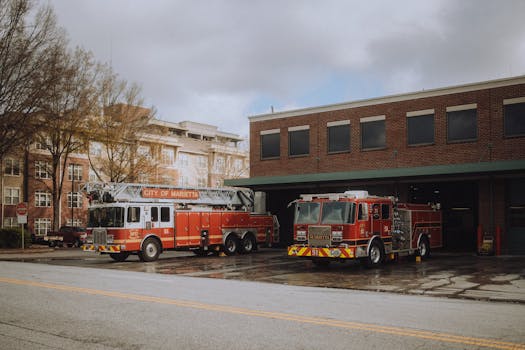 Fire trucks parked outside a Marietta fire station on a cloudy day, ready for action.