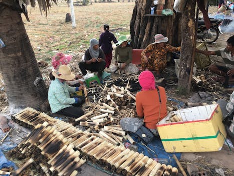 Group of people crafting bamboo products outdoors, showcasing local culture and community effort.